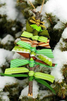 a christmas tree ornament made out of ribbon and bows is sitting on snow covered branches