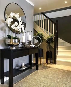 a table with vases and candles on it in front of a stair case next to a mirror