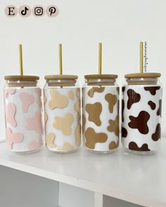 four jars with gold, pink, and brown dog prints are lined up on a table