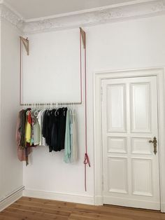 an empty room with some clothes hanging on the wall and two doors in the background