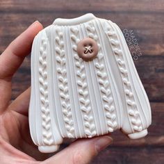 a hand holding a white ceramic object with a button on it's center piece