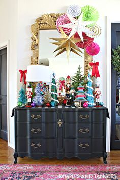 a christmas tree is on top of a dresser in front of a mirror and other decorations