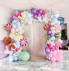 an arch made out of balloons and candy canes on a marble countertop in front of a white wall