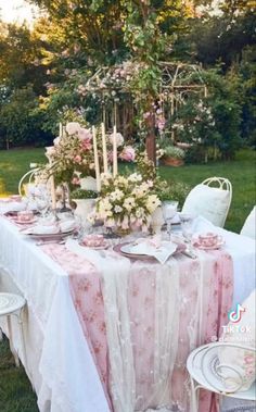 a table set up for a tea party with pink and white flowers on the table