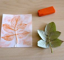 an orange stamp sits next to a leaf and a piece of paper on a table