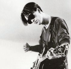 a young man playing an electric guitar in the middle of his body and wearing sunglasses