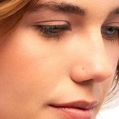 a close up of a woman with her eyes closed and nose piercings in front of her face