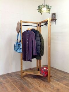 a coat rack with clothes hanging from it and a bag on the floor next to it