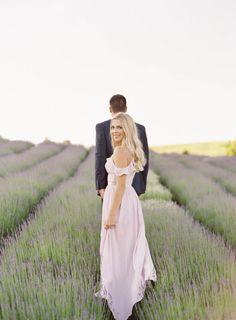 a man and woman standing in the middle of a lavender field