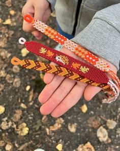 a person holding three bracelets in their hand with beads on the wrist and an orange clasp