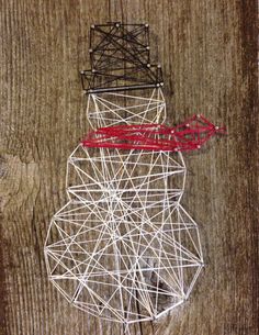 a snowman made out of string on top of a wooden table next to a red ribbon