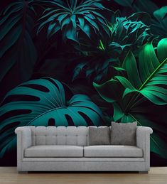 a couch sitting in front of a wall with green leaves on it and a black background