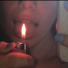 a woman holding a lighter in her mouth with the light on it's side