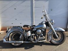 a silver motorcycle parked in front of a garage