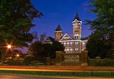 an old brick building with a clock tower in the middle of it's front yard