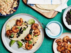 several plates of food on a table with blue and white dishes around them, including shrimp tacos