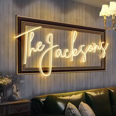 a neon sign that says the jacksons on it's wall next to a couch