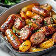 sausages and potatoes in a white casserole dish with parsley on top