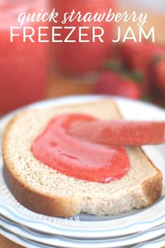 a piece of bread with jam on it sitting on top of a white plate next to some strawberries