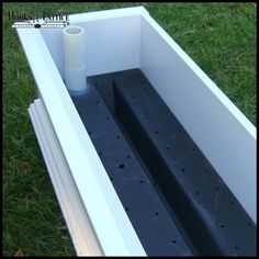 the bottom section of a white box with black plastic striping and two rolls of tape in it