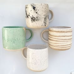 four coffee mugs sitting next to each other on top of a white countertop