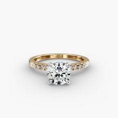 a yellow gold engagement ring with diamonds on the band and a round cut diamond in the center