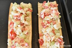 two long sandwiches with toppings sitting on a baking sheet