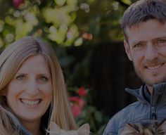 a man and woman standing next to each other with a cat in front of them