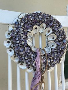 a wreath made out of seashells is hanging on the side of a railing