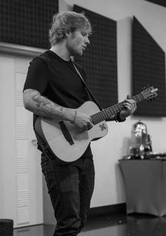 a man holding a guitar while standing in a room