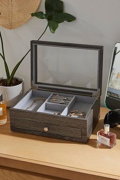 an open jewelry box sitting on top of a table next to a mirror and potted plant