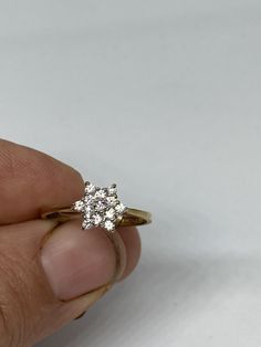 a hand holding a diamond ring in it's left hand on a white background