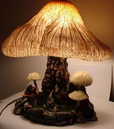 a lamp that is sitting on top of a table next to some rocks and mushrooms