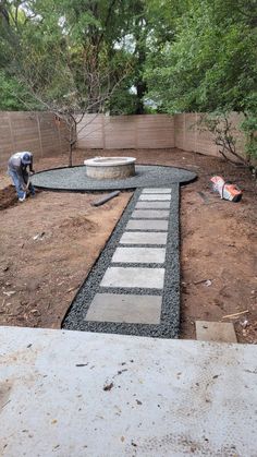 a man is working on a walkway in the yard with concrete blocks and pavers