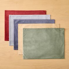 four different colored placemats sitting on top of a wooden table