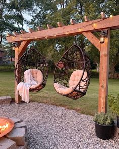 two hanging chairs in front of a fire pit