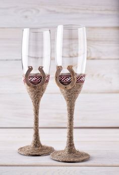 two wine glasses sitting on top of a wooden table next to each other with designs