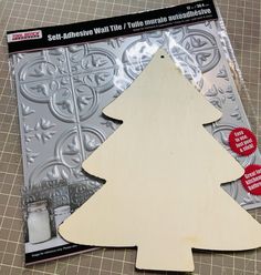 a wooden christmas tree cutout sitting on top of a piece of metal foil next to a package