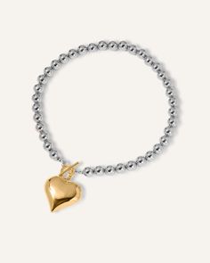 The Margaux Necklace features a striking large gold heart-shaped pendant suspended from a chic chain of silver beads. This unique combination of metals adds a modern and stylish touch to any ensemble enclosed with a toggle clasp. Make a bold statement with this eye-catching necklace that seamlessly blends sophistication and fashion-forward flair. 18k Gold Coated Length: 15" chain Thickness: 5mm Pendant: 50mm Toggle Clasp Hypoallergenic & non-tarnish Style Tips: The Margaux Necklace is a classic Love Bracelets, Magnetic Clasp, Toggle Clasp, Gold Heart, Style Tips, Heart Of Gold, Paper Clip, Silver Beads, Jewelry Care