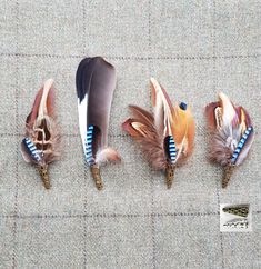 four feathers with blue and brown designs are lined up in a row on the ground