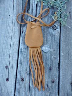 a tan leather purse sitting on top of a wooden table next to a blue plant