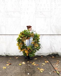 a woman standing in front of a wall with a wreath on it