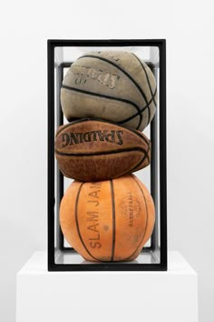 three basketballs are stacked on top of each other in a glass case with black trim