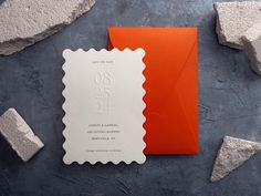 an orange and white wedding card with a postage stamp on the front next to it