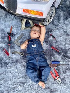 a baby laying on the ground next to tools