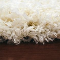 a white shaggy rug on top of a wooden floor