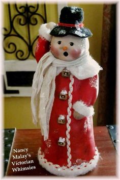 a red and white snowman figurine sitting on top of a wooden table