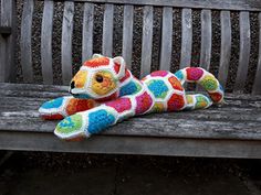 a colorful stuffed animal laying on top of a wooden bench