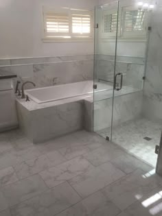 a bathroom with a tub, toilet and shower stall in white marbled flooring