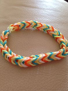 an orange, white and blue braided bracelet sitting on top of a table